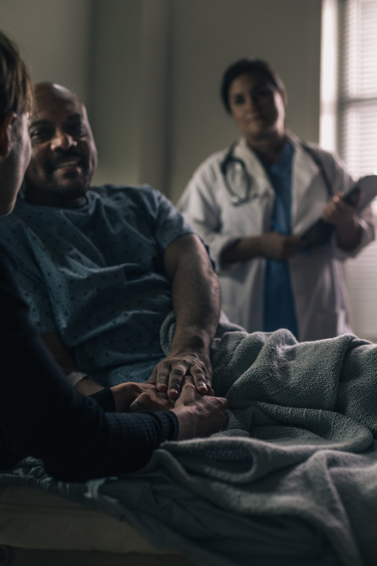 a male patient smiles while holding the hand of a friend scaled